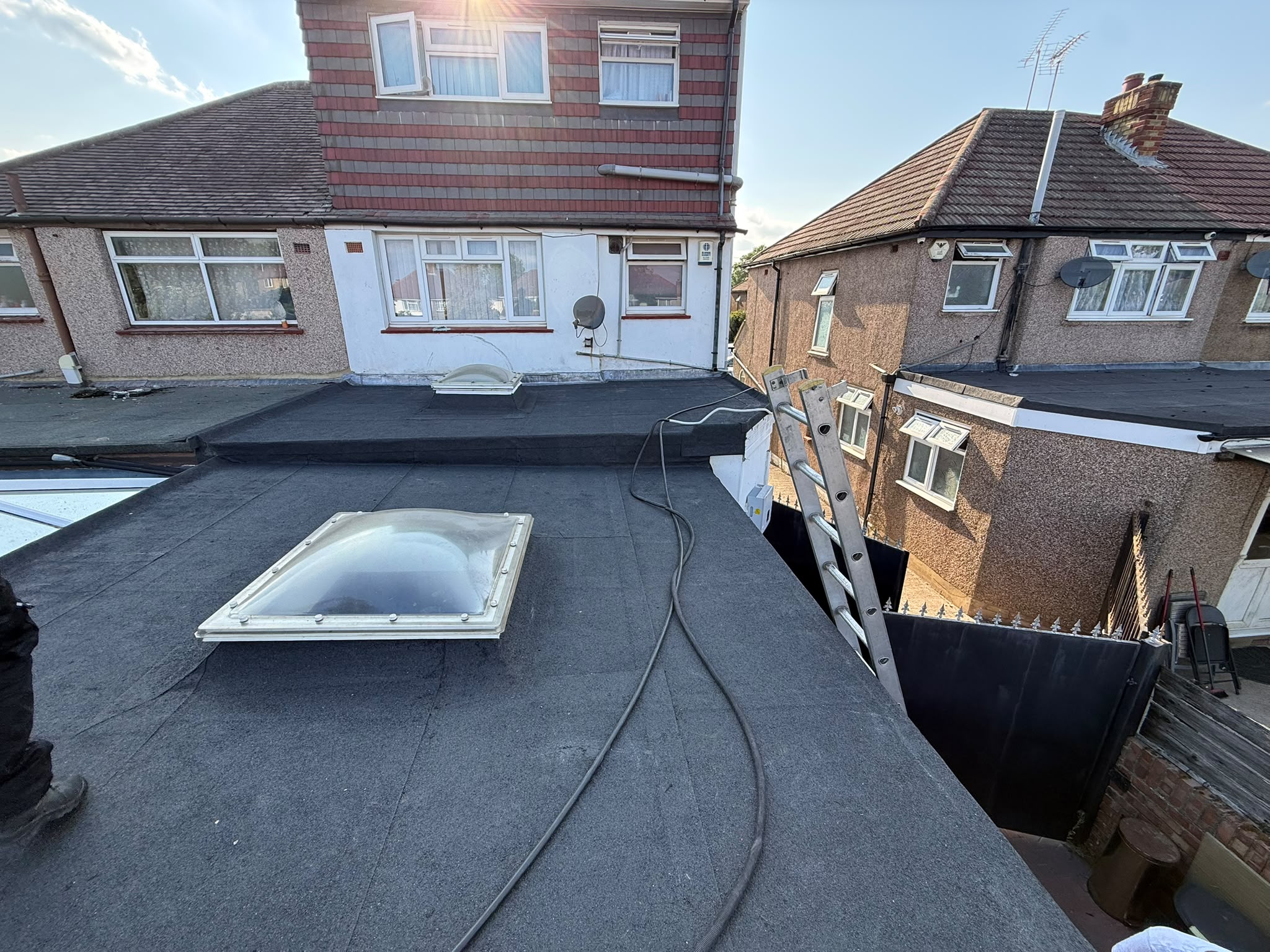Flat roof and rooflight beside a brick house
